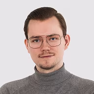 Adrian w szarym golfie i okularach